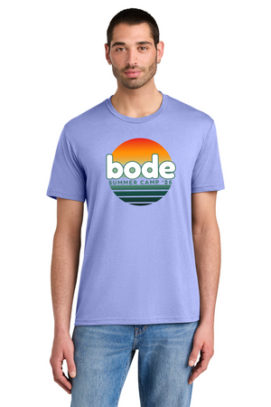 A man wears a Printify 2026 Bode Summer Bootcamp OG Logo Unisex T-Shirt DM130 Tri Blend in light purple, featuring a sunset graphic and "bode SUMMER CAMP '23" on the front, made of breathable tri-blend fabric.