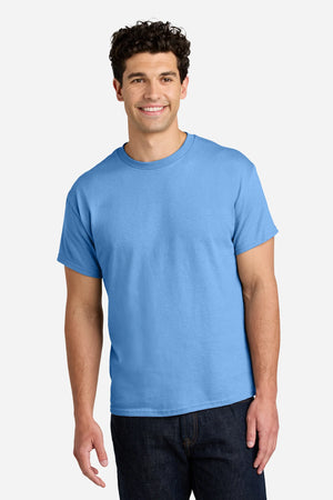 A man stands facing forward, smiling, wearing a Gildan 5000 Heavy 100% Cotton Custom T-Shirt (Pack of 36) with custom screen printed logo and dark jeans against a neutral background.
