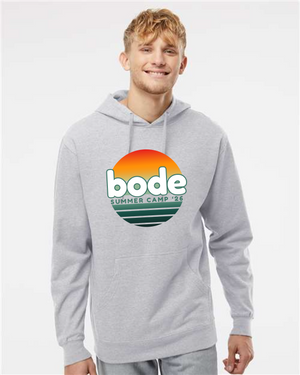 A young man wears a gray Printify 2026 Bode Summer Bootcamp OG Logo Hoodie Sweatshirt by Independent Trading Co. SS4500, featuring a sunset graphic on the front.
