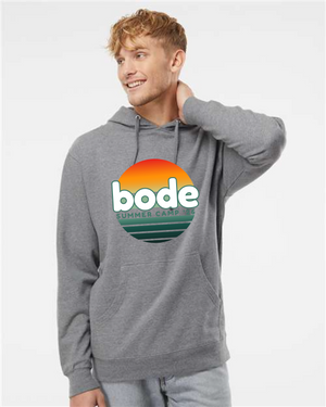 A person wears a Printify 2026 Bode Summer Bootcamp — OG Logo Unisex Hoodie Sweatshirt (Independent Trading Co. SS4500) featuring a colorful front logo, standing against a plain white background.