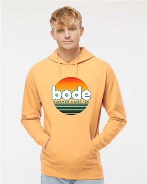 A young man wears a yellow Printify "2026 Bode Summer Bootcamp — OG Logo" unisex fleece hoodie (Independent Trading Co. SS4500) with an adjustable hood and front sunset graphic.