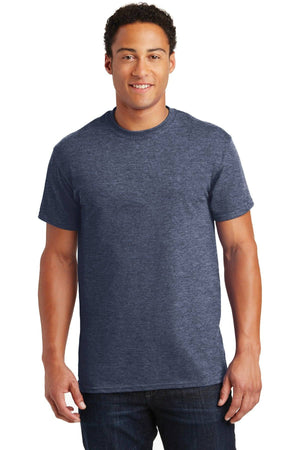 A person wearing a Gildan - 100% US Cotton T-Shirt 2000 in dark blue, paired with jeans, stands against a plain white background, smiling at the camera.