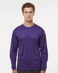 A person with short hair is wearing a long-sleeved, purple C2 Sport Performance Long Sleeve T-Shirt made from antimicrobial fabric and standing against a plain white background.