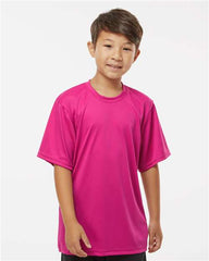 A young boy wearing a pink C2 Sport Youth Performance T-Shirt.