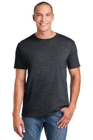 A smiling person stands with one hand in their pocket, wearing a dark gray Gildan Softstyle T-Shirt 64000, made from ring spun cotton, and blue jeans, showcasing a modern classic fit.