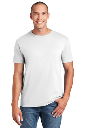 A person in a Gildan Softstyle T-Shirt 64000, made from ring spun cotton for comfort, and jeans smiles at the camera against a plain white backdrop.