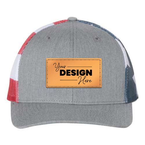 The Richardson 112PM Printed Mesh Trucker Cap is a gray mid-profile hat with red, white, and blue side panels, mesh back, adjustable snapback, cotton-polyester fabric, and a front patch reading "Your Design Here." Custom embroidery available.