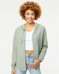 A woman wearing a green hoodie, showcasing the Independent Trading Co. Women's California Wave Wash Full-Zip Hoodie Sweatshirt with style and confidence in jeans.