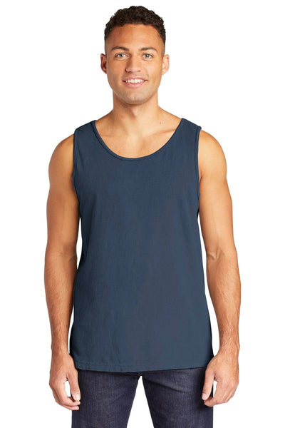 A person wearing a Comfort Colors Heavyweight Ring Spun Tank Top 9360 in dark blue and dark jeans, standing and smiling against a plain background.