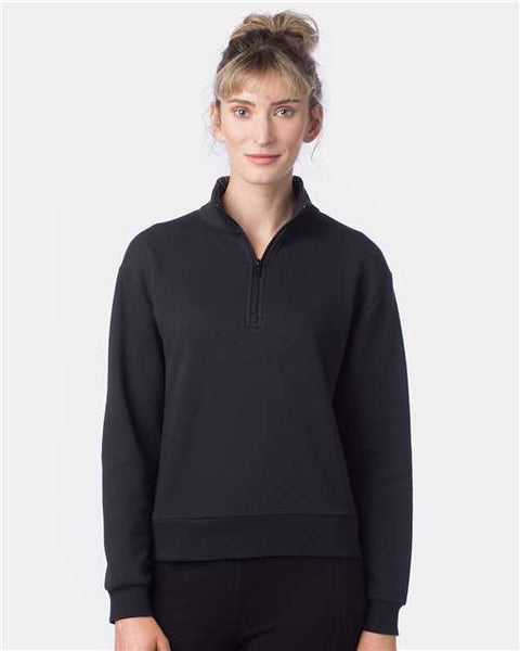 A woman wearing the Alternative Women's Eco-Cozy Fleece Quarter-Zip Sweatshirt in black, crafted from recycled polyester, stands with a slight smile against a plain white background.
