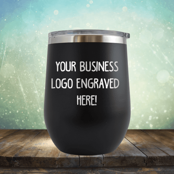 Customizable Kodiak Coolers black tumbler with a silver rim and a business logo laser engraved on a wooden surface with a bokeh background.