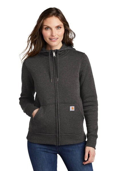 A woman, smiling at the camera in blue jeans, is wearing a Carhartt Women's Clarksburg Full-Zip Hoodie Sweatshirt CT102788—a dark gray Carhartt hoodie with front pockets.