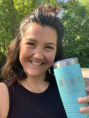 A woman holding a Kodiak Coolers Custom Tumblers 20 oz with your Logo or Design Engraved - Special Black Friday Sale Volume Pricing - LIMITED TIME, with the word infinity laser engraved on it.