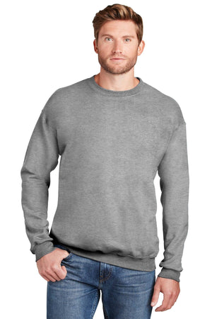 A man is standing against a white background with one hand in his pocket, wearing blue jeans and a Hanes Ultimate 100% Cotton Crewneck Sweatshirt F260.