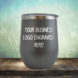 Customizable Kodiak Coolers stainless steel tumbler with engraved drinkware space for a business logo on a wooden surface against an illuminated backdrop.