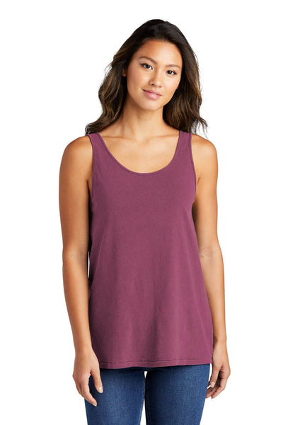 A woman wearing a Port & Company Ladies Beach Wash Garment-Dyed Tank Top (LPC099TT) in mauve and blue jeans stands facing the camera against a plain white background.