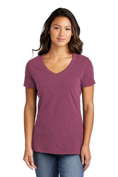 A person wearing a Port & Company Ladies Beach Wash Garment-Dyed V-Neck T-Shirt LPC099V and blue jeans stands, smiling against a plain white background.