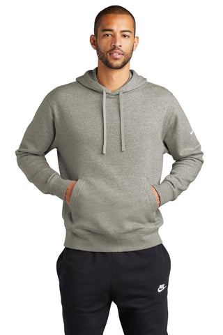 A man in a grey Nike Club Fleece Sleeve Swoosh Pullover Hoodie Sweatshirt (NKDR1499) and black pants embodies a casual street-ready look, standing with his hands in his pockets.