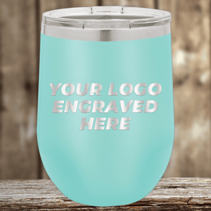 A light blue stainless steel tumbler by Kodiak Coolers with a clear lid, engraved with your custom company logo—ideal Realtor closing gifts for clients or personalized drinkware—set against a wooden background.