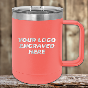 A coral Kodiak Coolers insulated mug with handle and clear lid, custom engraved with your company logo—perfect as a Realtor closing gift for clients or a unique promotional item. Shown on a wooden surface with a blurred wood background.