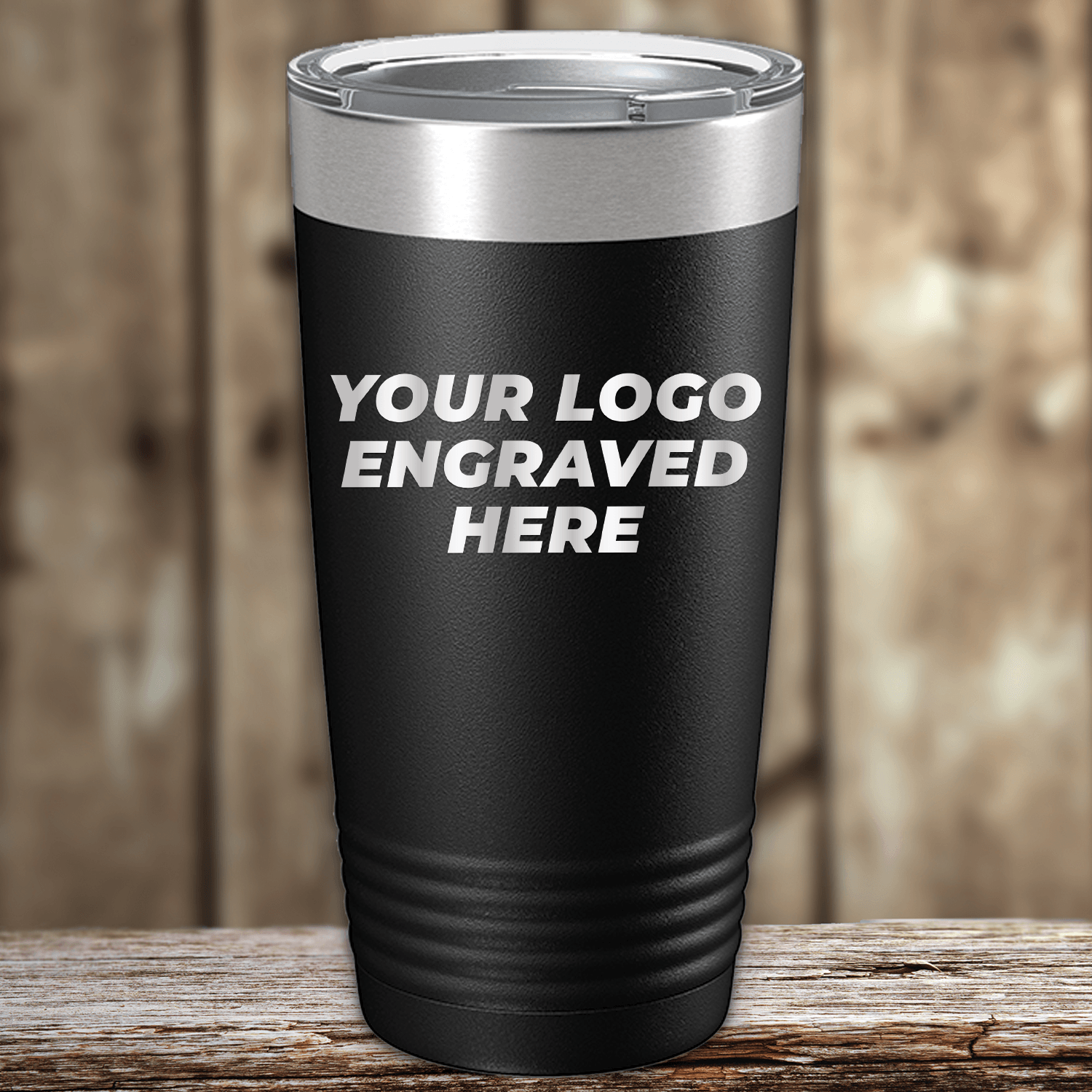 A black Kodiak Coolers tumbler with a silver lid sits on a wooden surface, featuring "YOUR LOGO ENGRAVED HERE"—ideal as Realtor Closing Gifts for Clients seeking custom company logo drinkware.