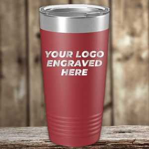 A red Kodiak Coolers tumbler with a silver lid, engraved with "YOUR LOGO ENGRAVED HERE," sits on a wooden surface—a perfect Realtor closing gift for clients seeking custom branded drinkware.