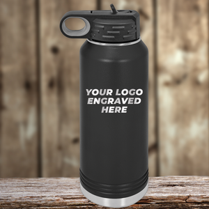 A black metal water bottle from Kodiak Coolers with your custom company logo engraved sits on a wooden surface—an ideal Realtor closing gift to pair with branded drinkware for clients.