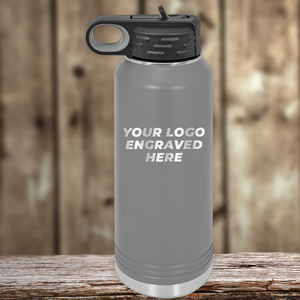 A gray Kodiak Coolers drinkware with a black lid, engraved with your custom company logo, sits on wood—perfect as a Realtor closing gift for clients or paired with personalized mugs.