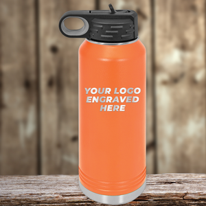 An orange insulated water bottle by Kodiak Coolers with your custom company logo engraved, ideal as a Realtor closing gift for clients, featuring a black lid and showcased on a wooden surface against a wood background.
