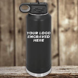 A black Kodiak Coolers insulated water bottle with a handle and your custom company logo engraved on the front, shown on a wooden surface—ideal as Realtor closing gifts or for adding to your promotional drinkware collection.