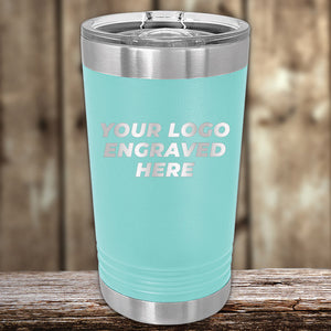 Customizable Kodiak Coolers aqua-colored tumbler with an engraved logo area on a wooden surface.
