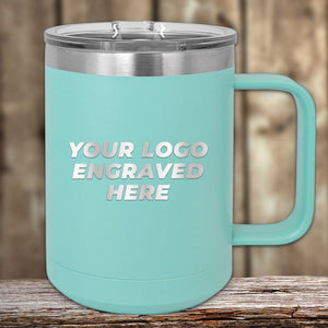 A turquoise Kodiak Coolers Engraved Custom Logo Drinkware mug with handle and clear lid, featuring single side engraving, is shown on a wooden surface with a blurred wood background. Bulk tiered pricing included.