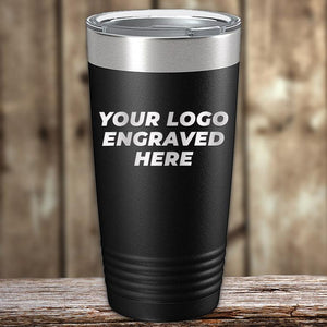 Black insulated tumbler with customizable text "your logo engraved here" on it, displayed on a wooden surface with a blurred background, ideal for corporate promotional gifts from Kodiak Coolers.