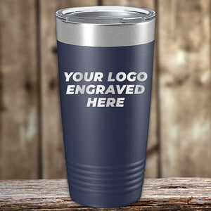 A navy Engraved Custom Logo Drinkware tumbler by Kodiak Coolers with a metal lid sits on wood, featuring "YOUR LOGO ENGRAVED HERE." Single side engraving is included; ideal for bulk custom or personalized mugs to display your brand.