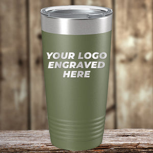A green Kodiak Coolers tumbler with "YOUR LOGO ENGRAVED HERE" on the front sits on wood; this Engraved Custom Logo Drinkware includes single side engraving in the price and bulk tiered pricing—ideal for personalized mugs.