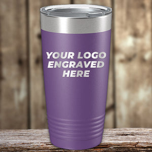 A purple Kodiak Coolers Engraved Custom Logo Drinkware tumbler with a silver lid, featuring "YOUR LOGO ENGRAVED HERE" on one side, rests on wood—ideal for those wanting personalized mugs; bulk pricing available.