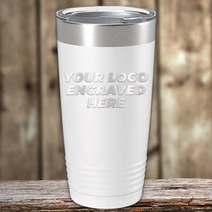 A Kodiak Coolers stainless steel tumbler with a placeholder text "your engraved logo here" on a wooden surface.