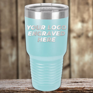 Light blue Kodiak Coolers custom tumblers engraved with "your logo here" text on a wooden surface.