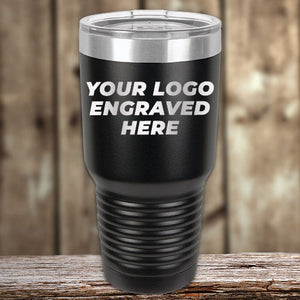 Stainless steel insulated tumbler from Kodiak Coolers, a perfect corporate promotional gift, with "your logo engraved here" text, displayed on a wooden surface.