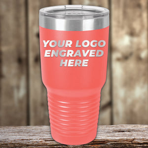 The Kodiak Coolers Engraved Custom Logo Drinkware features single-side engraving included in the price. Shown: a pink insulated tumbler with silver lid on wood, displaying "YOUR LOGO ENGRAVED HERE"—ideal for stylish custom mugs in bulk.