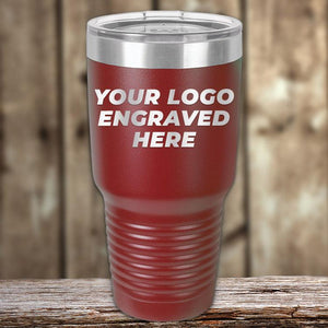 Red insulated Custom Tumblers engraved with your logo or design, displayed on a wooden surface with a blurred wooden background, ideal for corporate promotional gifts from Kodiak Coolers.