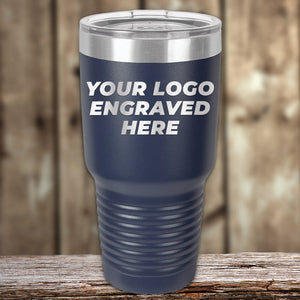 A navy blue Kodiak Coolers tumbler with a clear lid sits on a wooden surface, laser engraved with your logo—New Years Sale: custom drinkware, no setup fee, 1 side logo included. Perfect promotional gift or personalized mug.