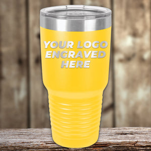 A yellow Kodiak Coolers tumbler from the New Years Sale sits on a wooden surface, featuring "YOUR LOGO ENGRAVED HERE." Custom laser engraving and 1 side logo included—no setup fee. Perfect promotional gift for businesses.