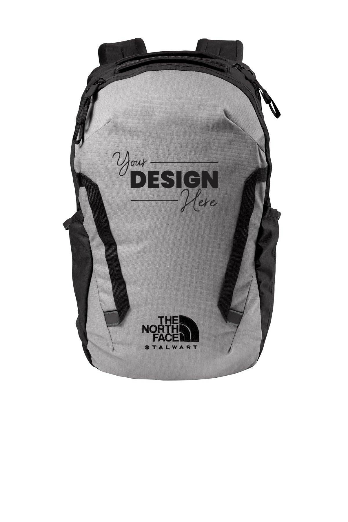 The North Face Stalwart Backpack (NF0A52S6) is a gray bag with black accents, prominently displaying "Your Design Here" and "The North Face Stalwart" logos on the front. It features a laptop sleeve in one of its two zippered compartments, and is crafted from recycled polyester material with a water-repellent finish for enhanced durability and sustainability.